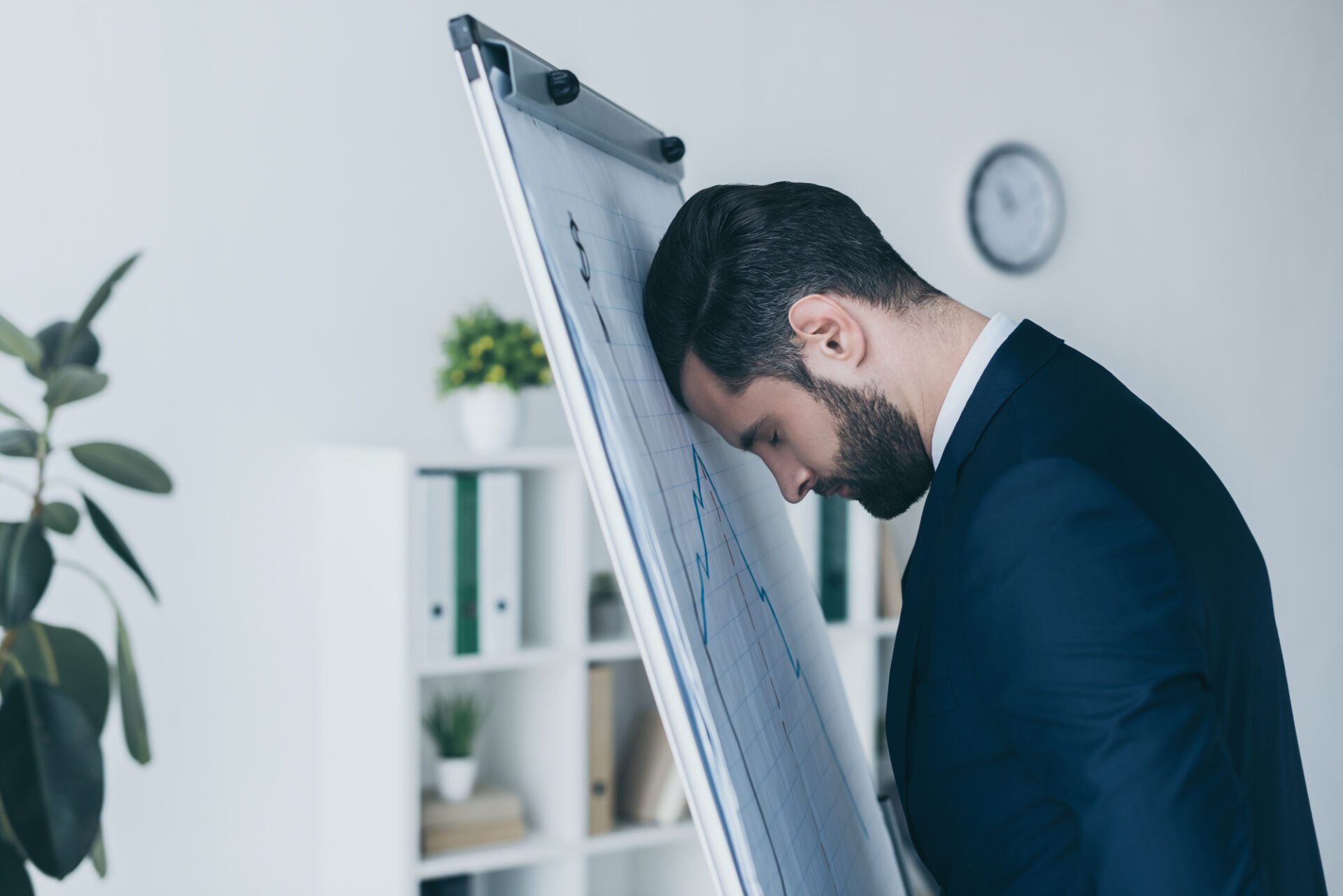 Upset businessman standing with closed eyes and leaning at flipchart