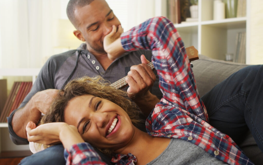 Happy couple lying on couch laughing