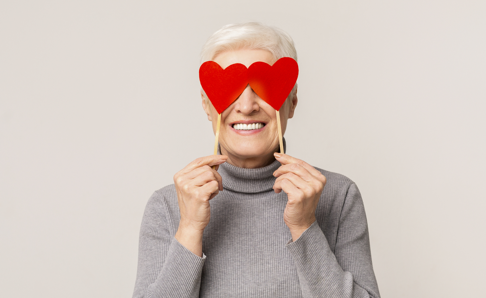 Happy woman covering her eyes with red paper hearts