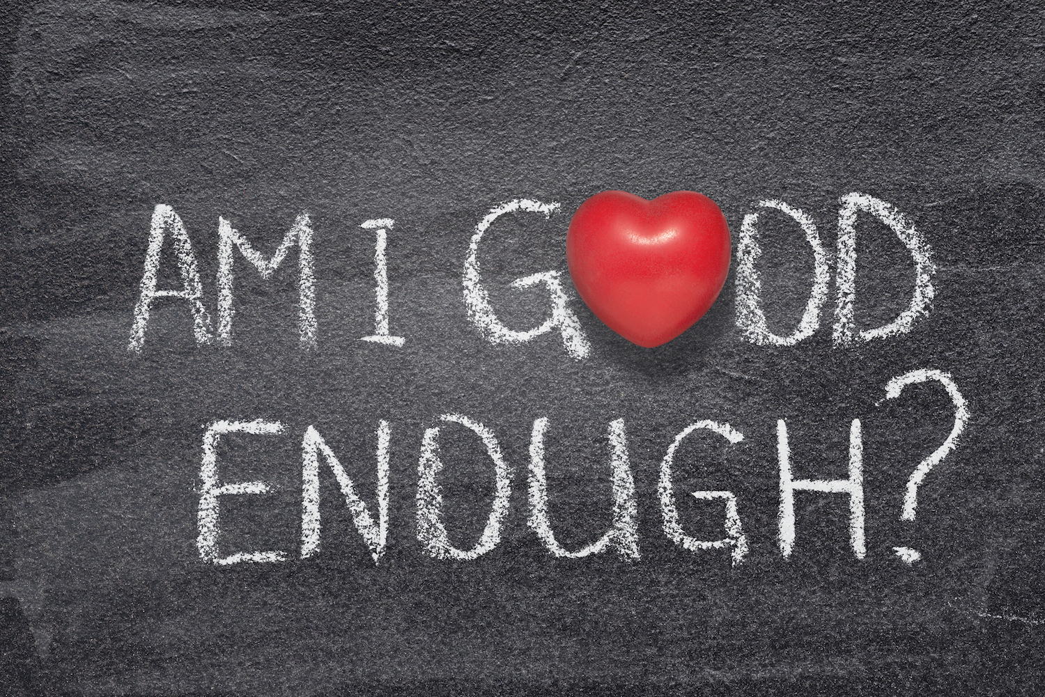 am I good enough question handwritten on chalkboard with red heart symbol