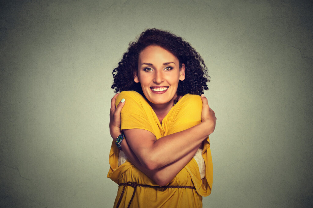 happy smiling woman holding hugging herself