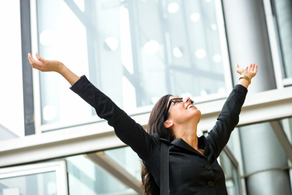 Woman business success with arms raised