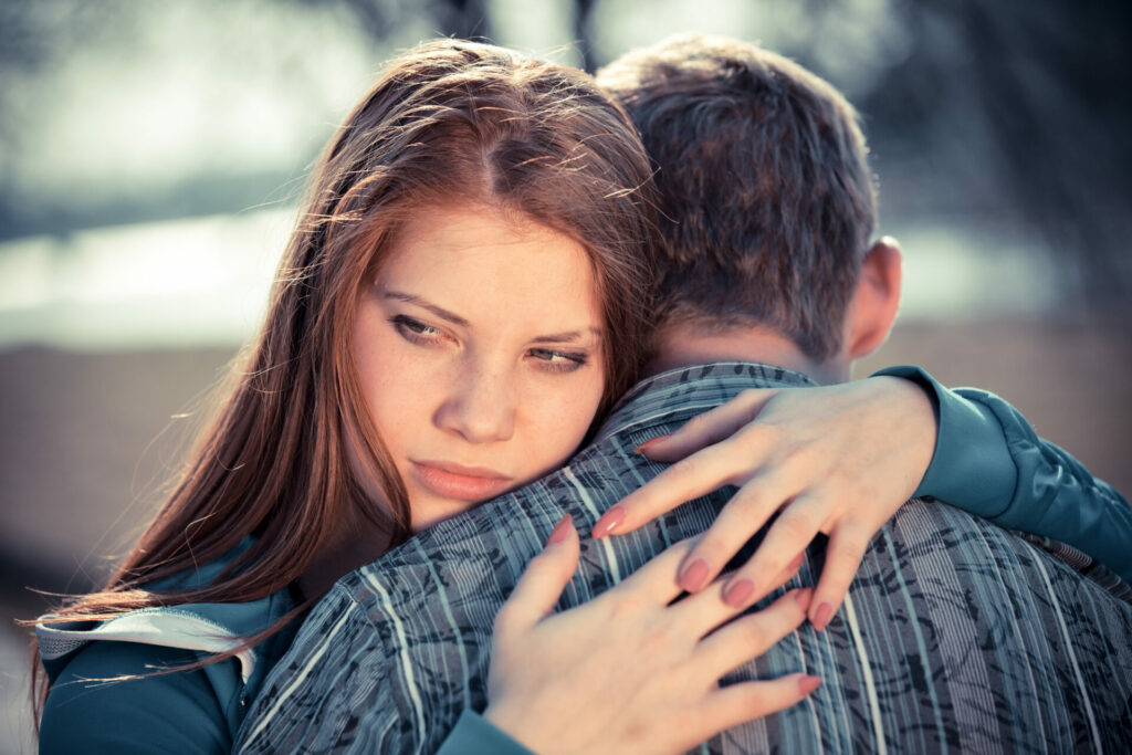unhappy woman hugging a man and looking off to the distance