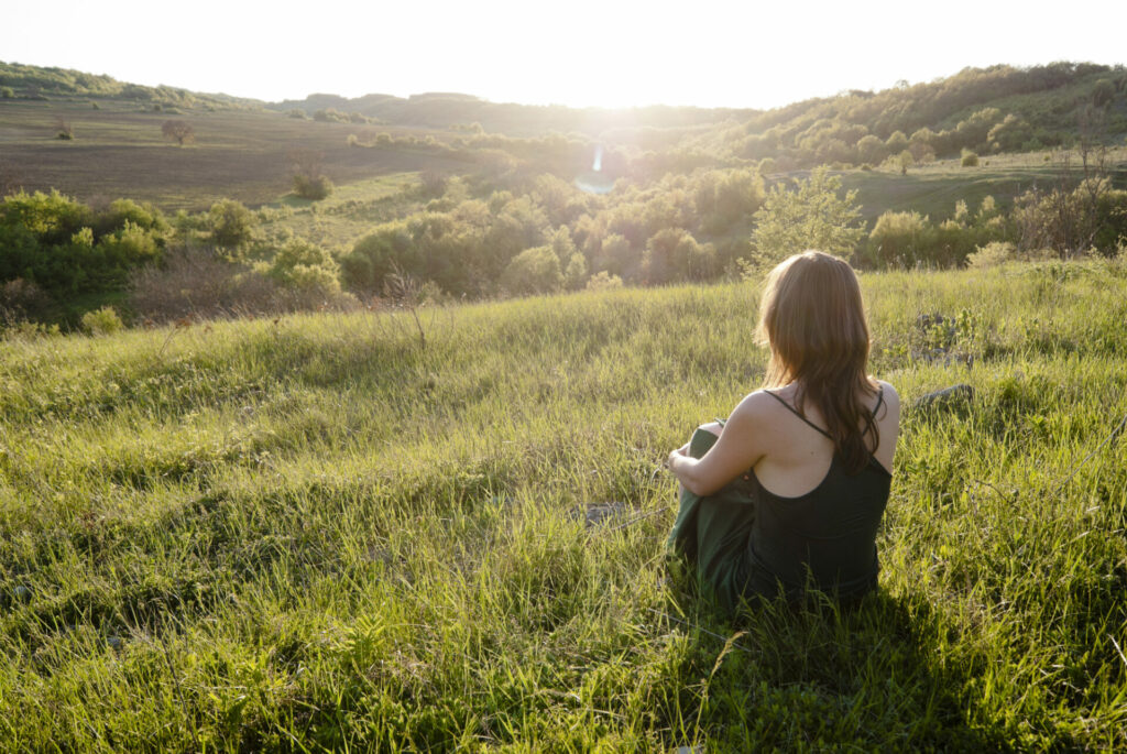 Gratitude - woman on grassy hill looking at nature