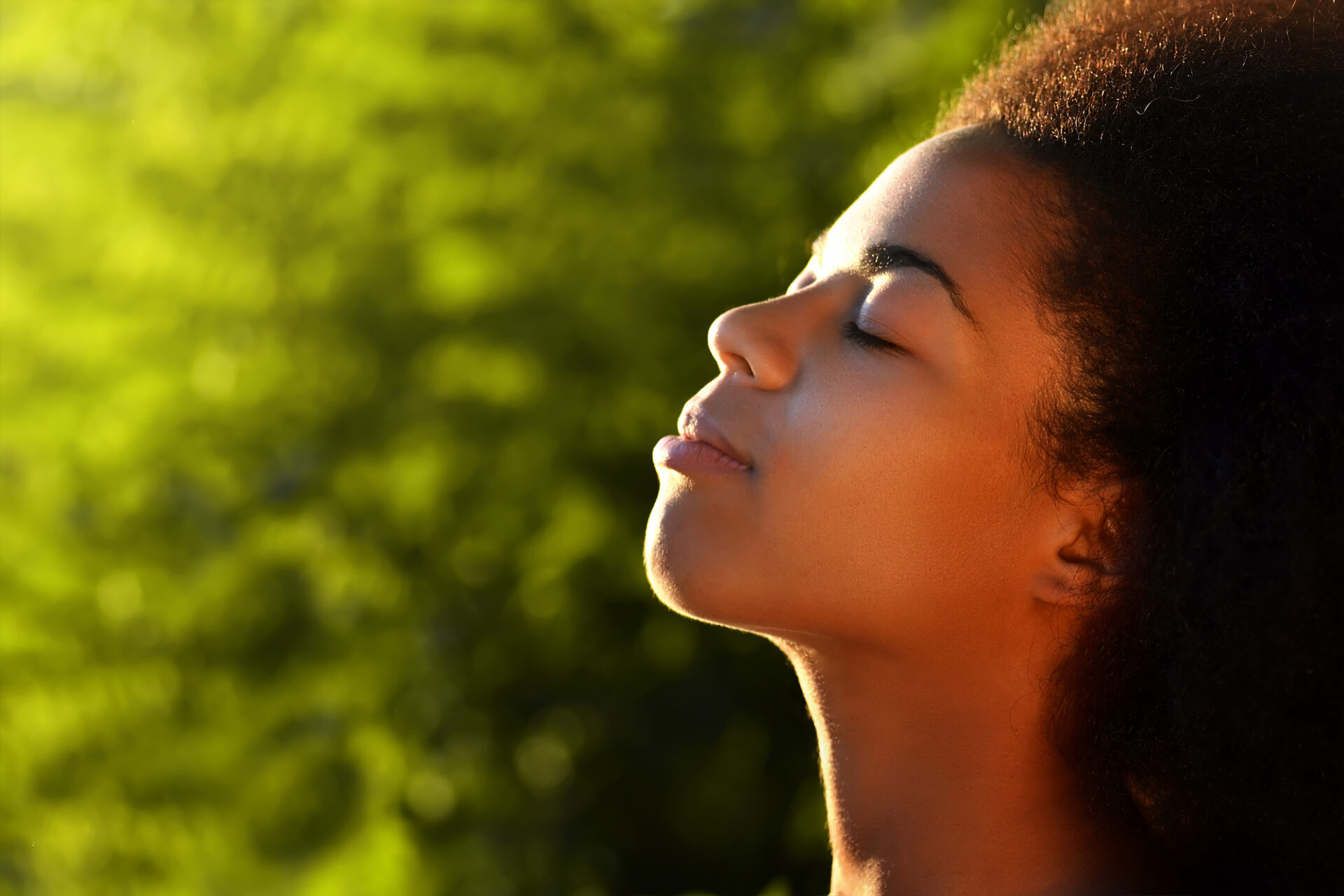 Young afro woman close up with sun on face - self-forgiveness