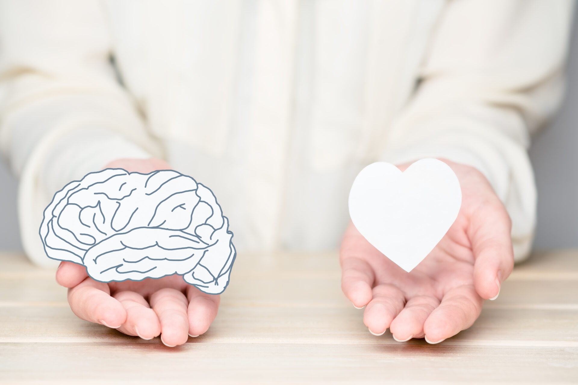 Two hands holding icons of a brain and a heart - Emotional Fears